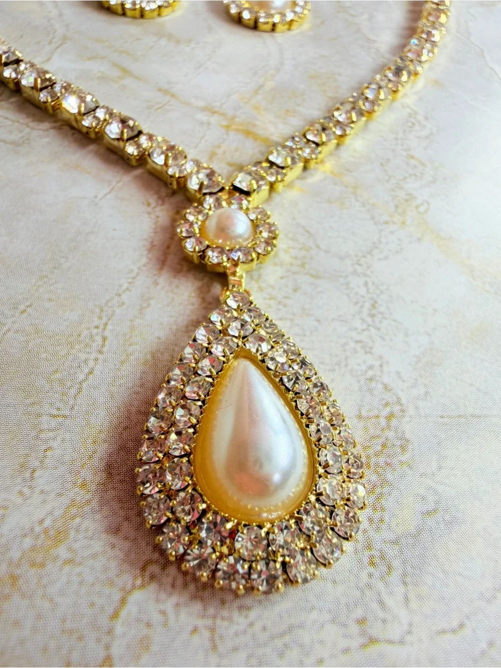Elegant gold-tone necklace with earrings featuring a white teardrop pearl pendan